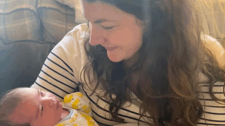 Beth wearing a stripy t-shirt, holding Joshua and smiling at him.