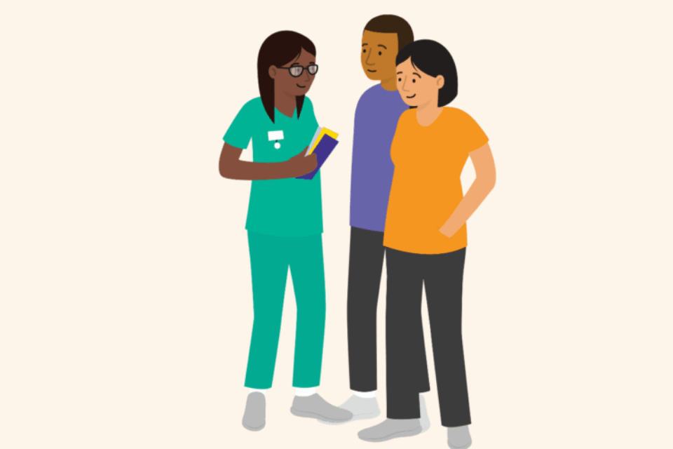A health professional speaks with a couple. The woman is pregnant. The couple are looking and engaging with the health professional, who is holding booklets in her hand.