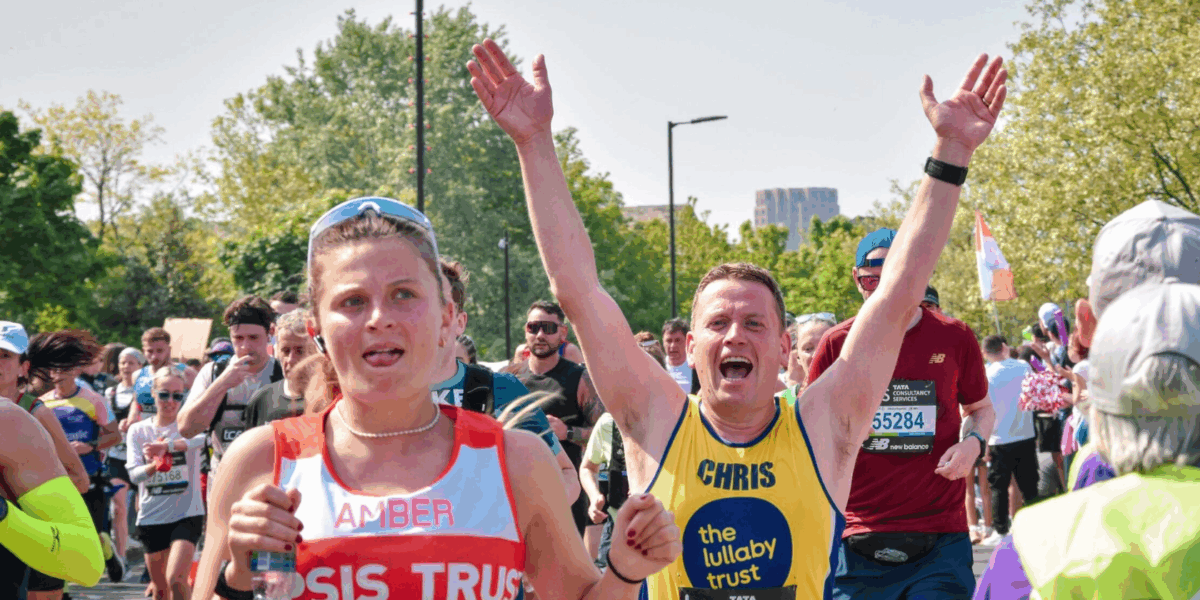 Marathon runner wearing Lullaby Trust vest cheering with his arms up in the air, running the race.