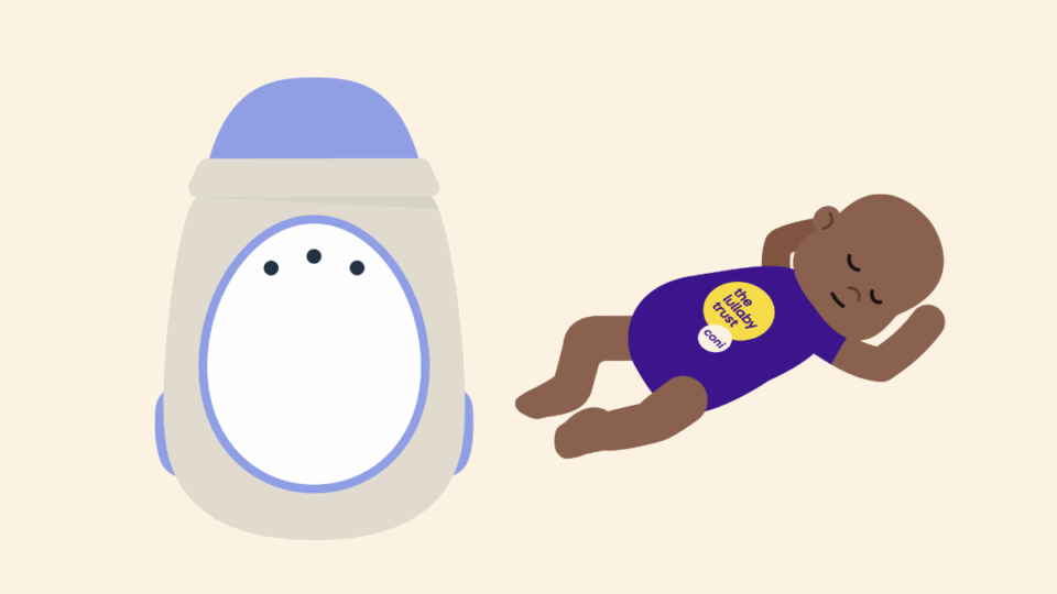 A movement monitor. It is an egg shaped monitor in cream with a white oval on it. There is a baby sleeping next to it wearing a CONI baby grow.