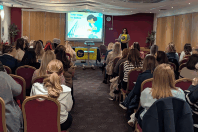 A seminar room full of people on seats, facing a Lullaby Trust staff member standing at the front.