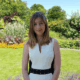 Ruth standing outdoors wearing a white dress.
