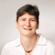 Jo Garstang wearing a white shirt and a necklace, smiling at the camera.