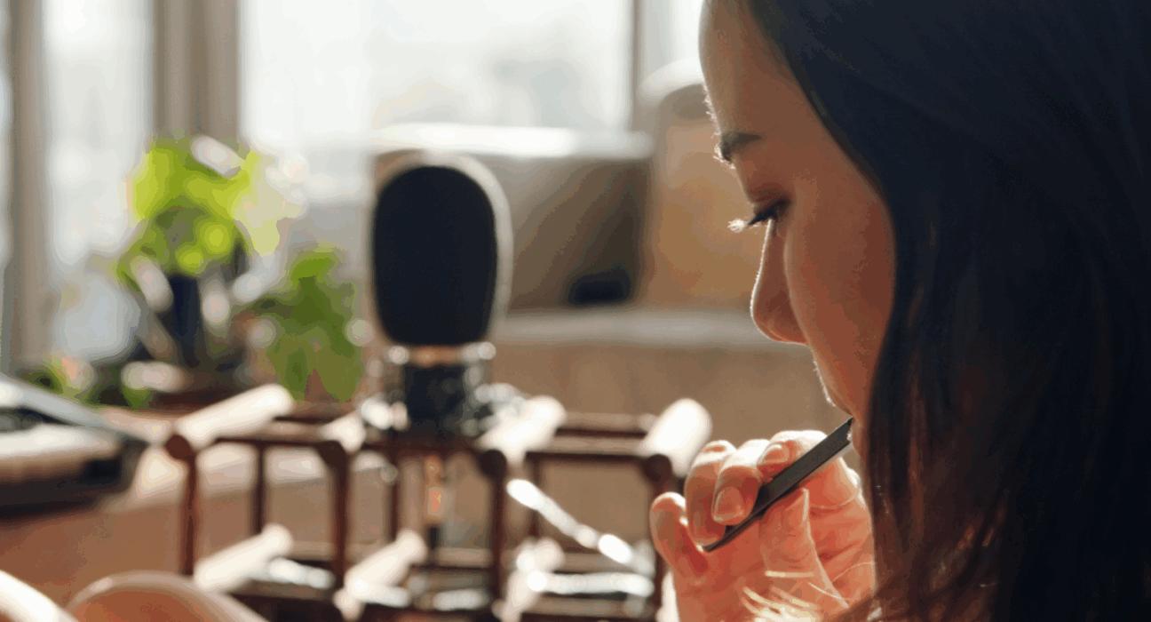 A woman is looking down at something on her lap, sat in her home whilst vaping.