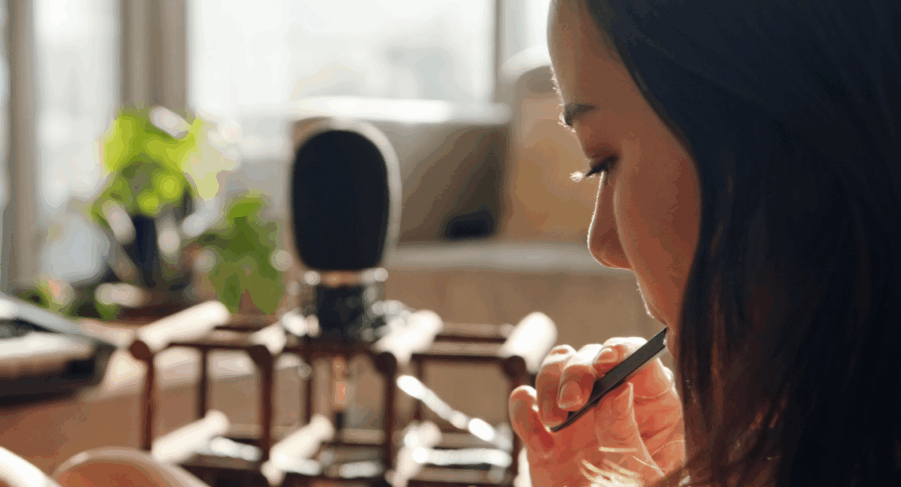 A woman is looking down at something on her lap, sat in her home whilst vaping.