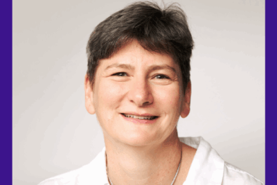 A professional headshot of Dr Joanna Garstang. She has short, dark hair, wears a white blouse, a silver necklace and is smiling.