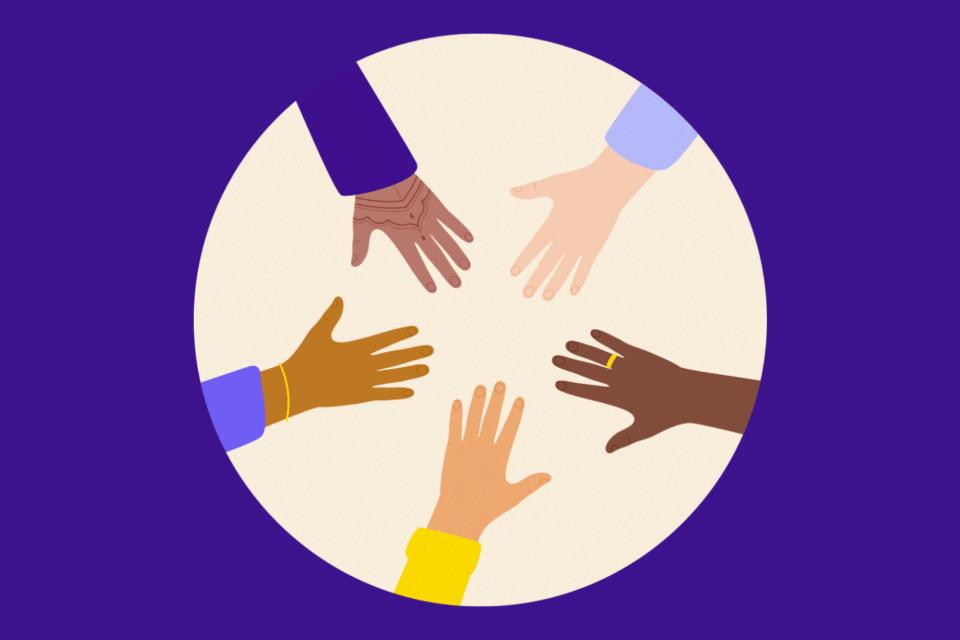 Different hands put together in a circle. Each hand is different, one has henna, some have jewelry, and they are all different skin tones.