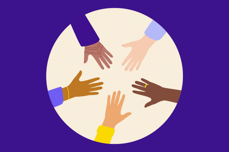 Different hands put together in a circle. Each hand is different, one has henna, some have jewelry, and they are all different skin tones.