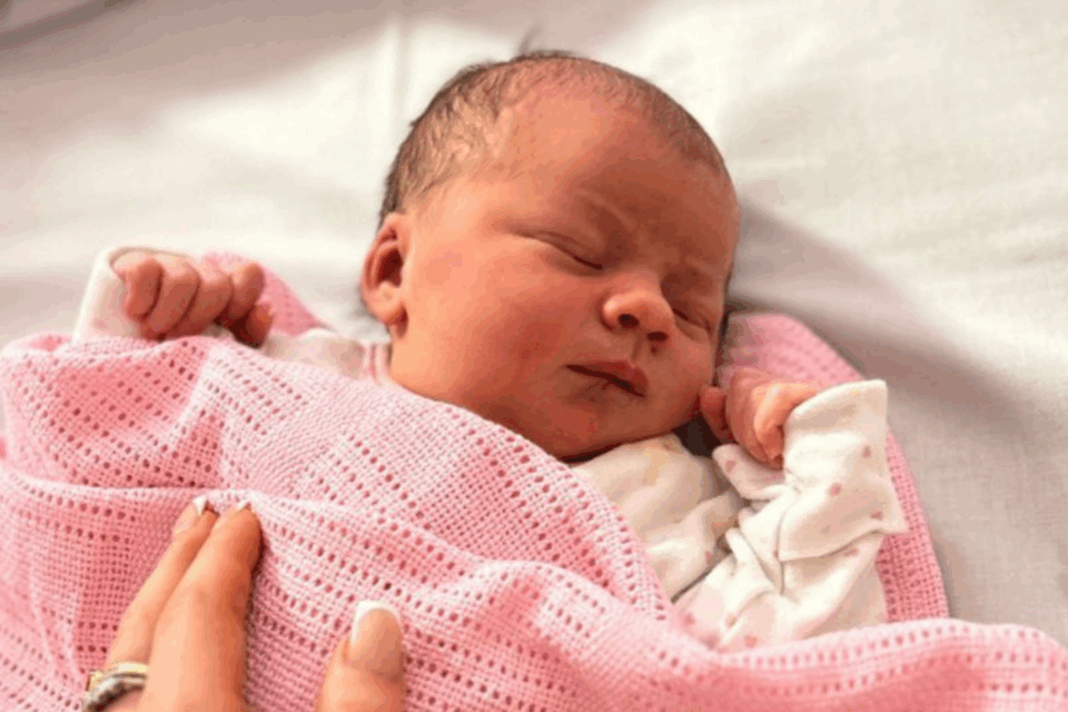 Baby Violet asleep on her back with a pink blanket on her.