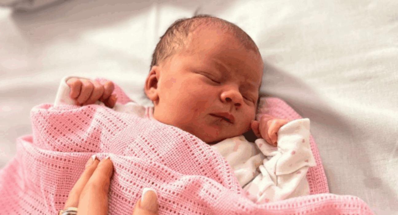 Baby Violet asleep on her back with a pink blanket on her.