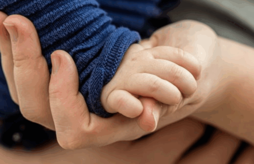 Baby's hand on an adult's hand, close up.