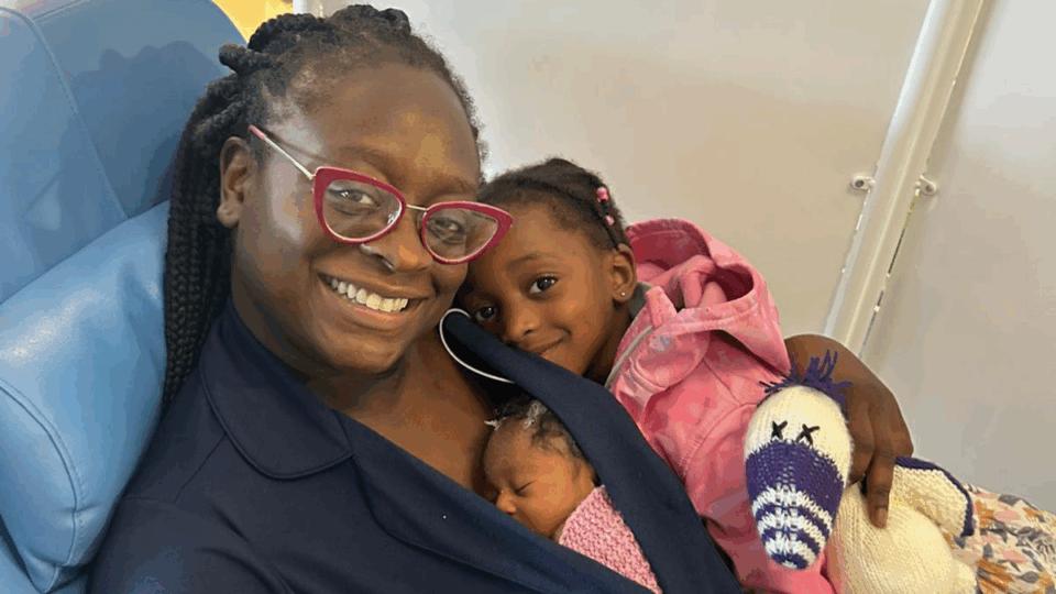 Seyi sitting on a chair with two of her children lying on her.