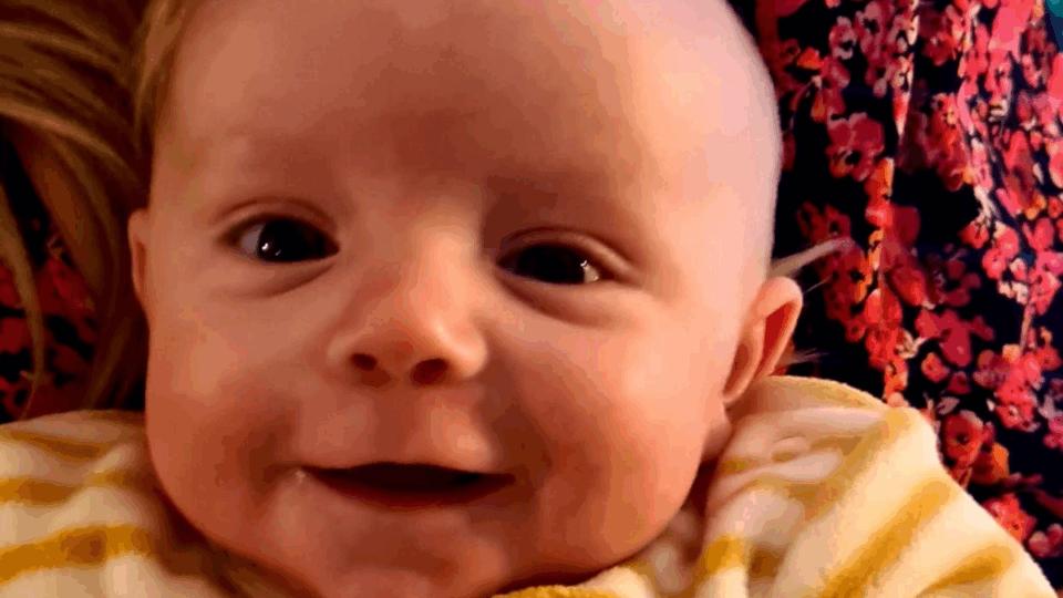 Jenson wearing a stripy babygrow smiling at the camera.