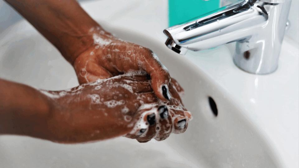 Close up of someone washing their hands with soap and water.
