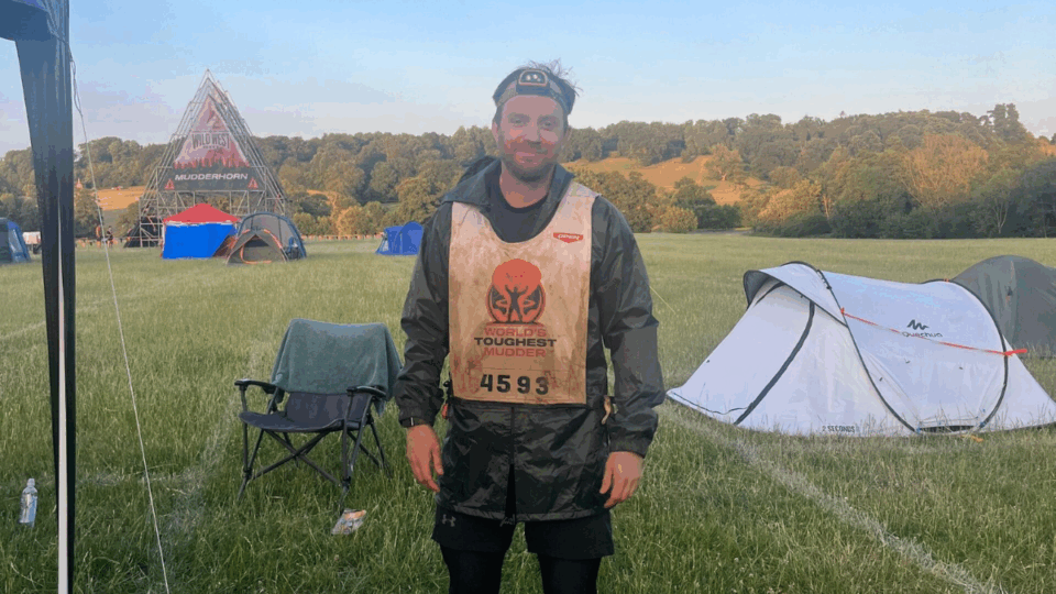 Stefan wearing a head torch and a vest, with a tent in the background.