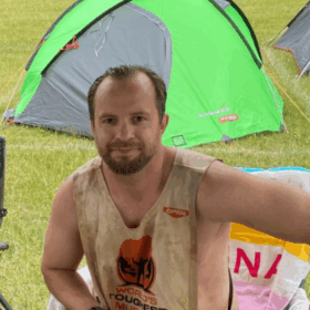 Stefan and a friend sitting on chairs in muddy t-shirts