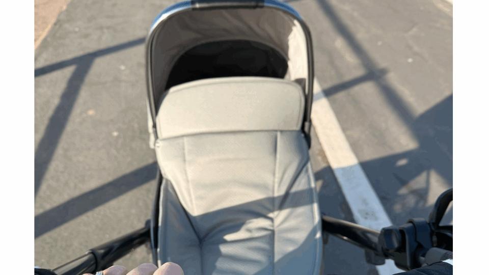 Becky with her hand on the buggy, pushing the buggy along the street on a sunny day.