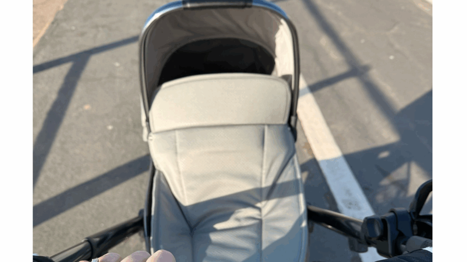Becky with her hand on the buggy, pushing the buggy along the street on a sunny day.