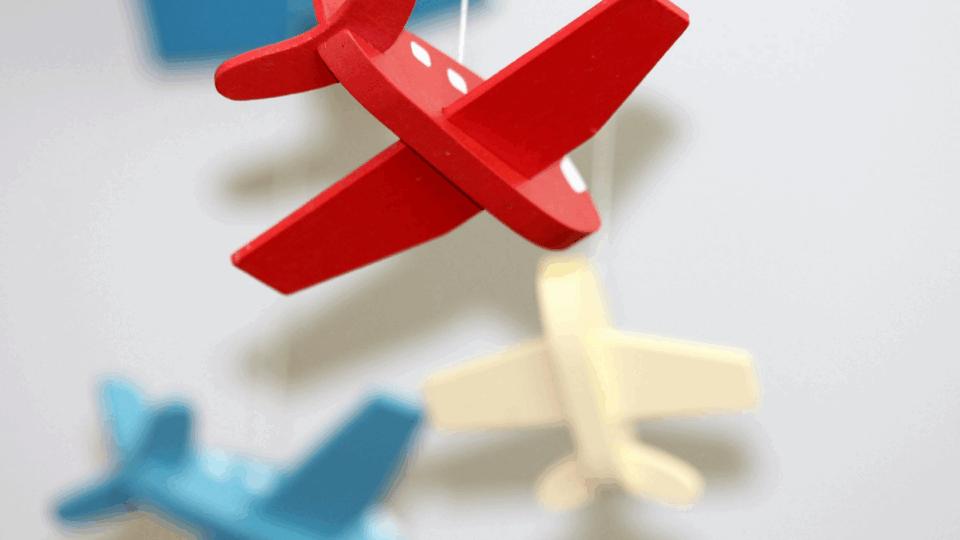 Close up of a baby's mobile. Three toy airplanes, one blue, one right, and one red.