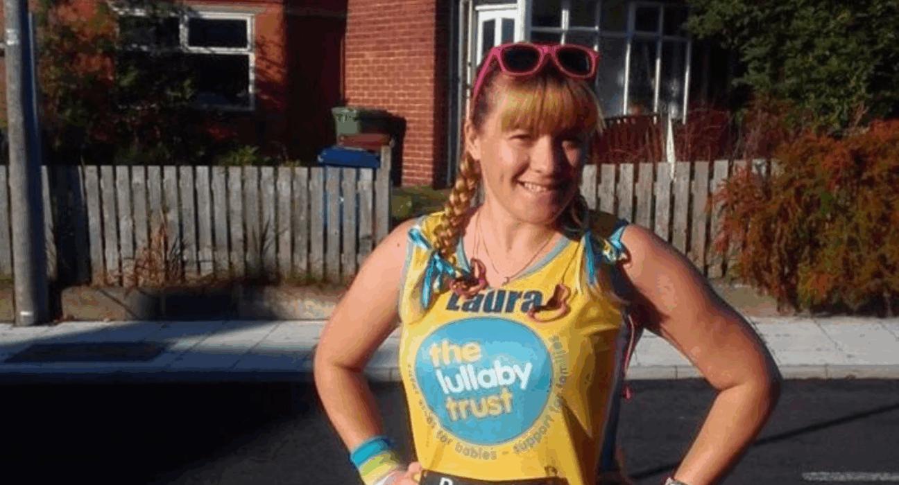 Laura wearing a Lullaby Trust running vest, smiling at the camera with her hands on her hips. She has pink sunglasses on her head and bows in her hair.