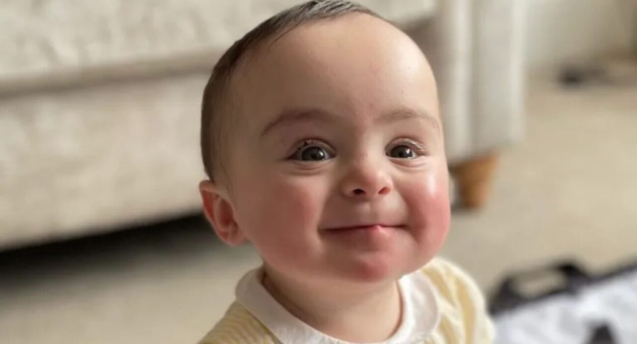 Gigi grins brightly wearing a yellow dress.
