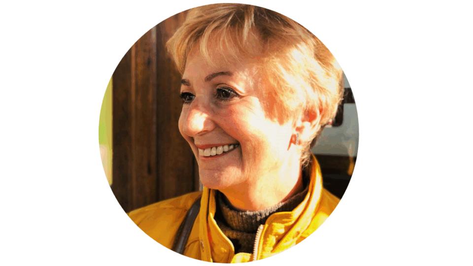 Close up of Judi, with blond hair, smiling away from the camera.