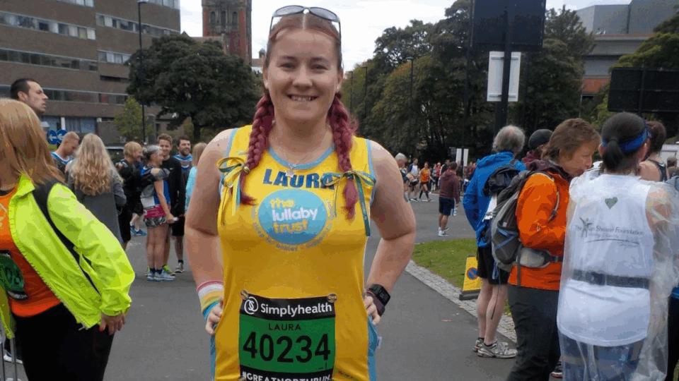 Laura wearing a Lullaby Trust running vest, standing on the street.
