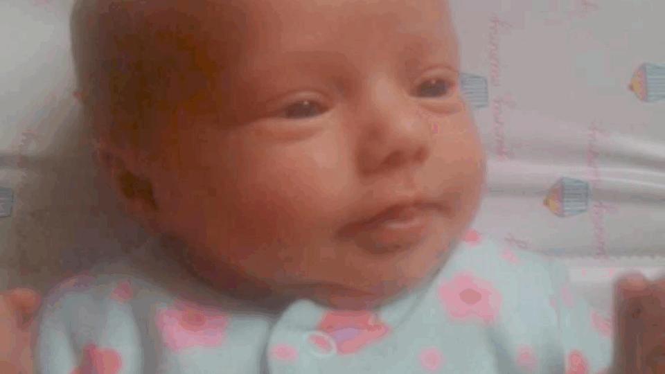 Close up of baby Jessie wearing a babygrow with pink flowers on.