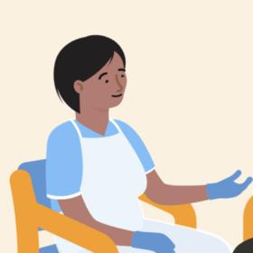 A health professional sitting on a chair, opposite a mum sitting on a chair with her baby on her lap, having a conversation.