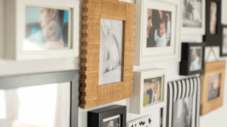 A wall of family photos in frames, mostly of young babies.