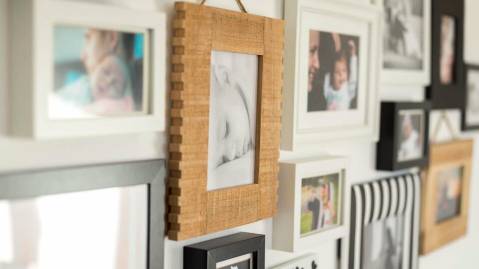 Several photo frames hanging on a wall, displaying photos of a baby.
