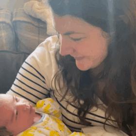 Beth wearing a stripy t-shirt, holding Joshua and smiling at him.