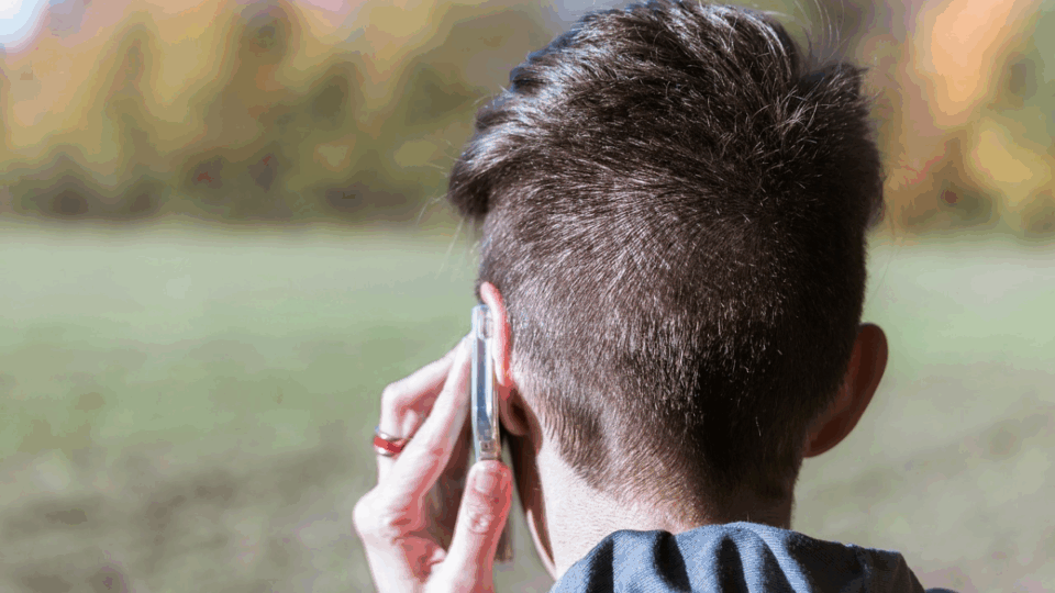 Person with their back to us, holding a phone to their ear.