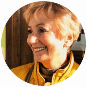 Close up of Judi, with blond hair, smiling away from the camera.