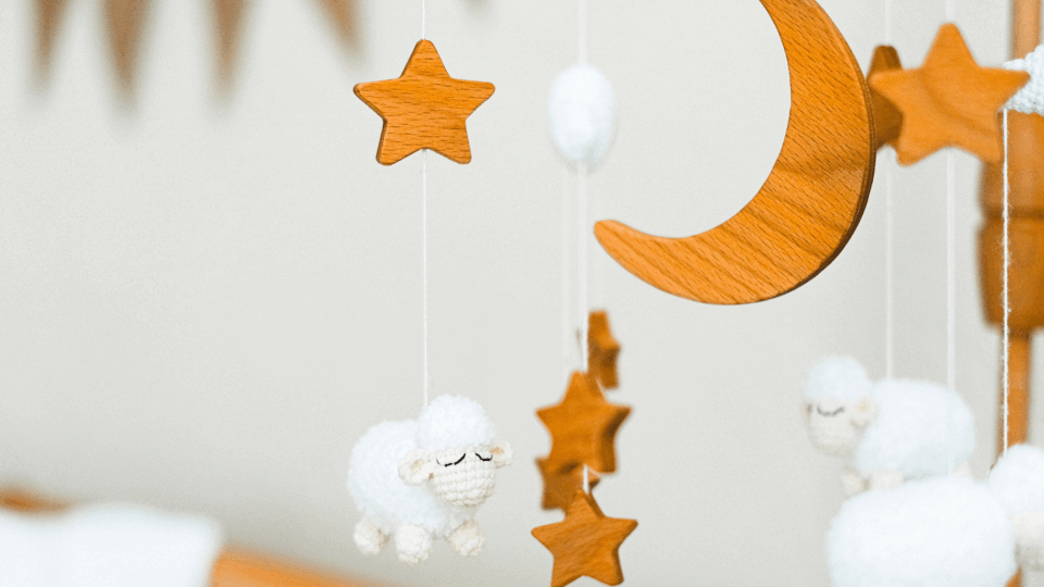 Dangling toys above a babys crib with stars, woolen sheep and moons.