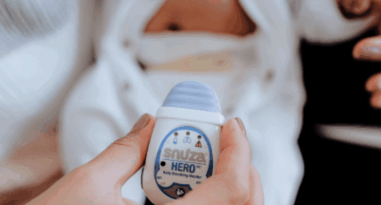 Snuza HeroMD monitor being held up with a baby in a babygrow in the background.