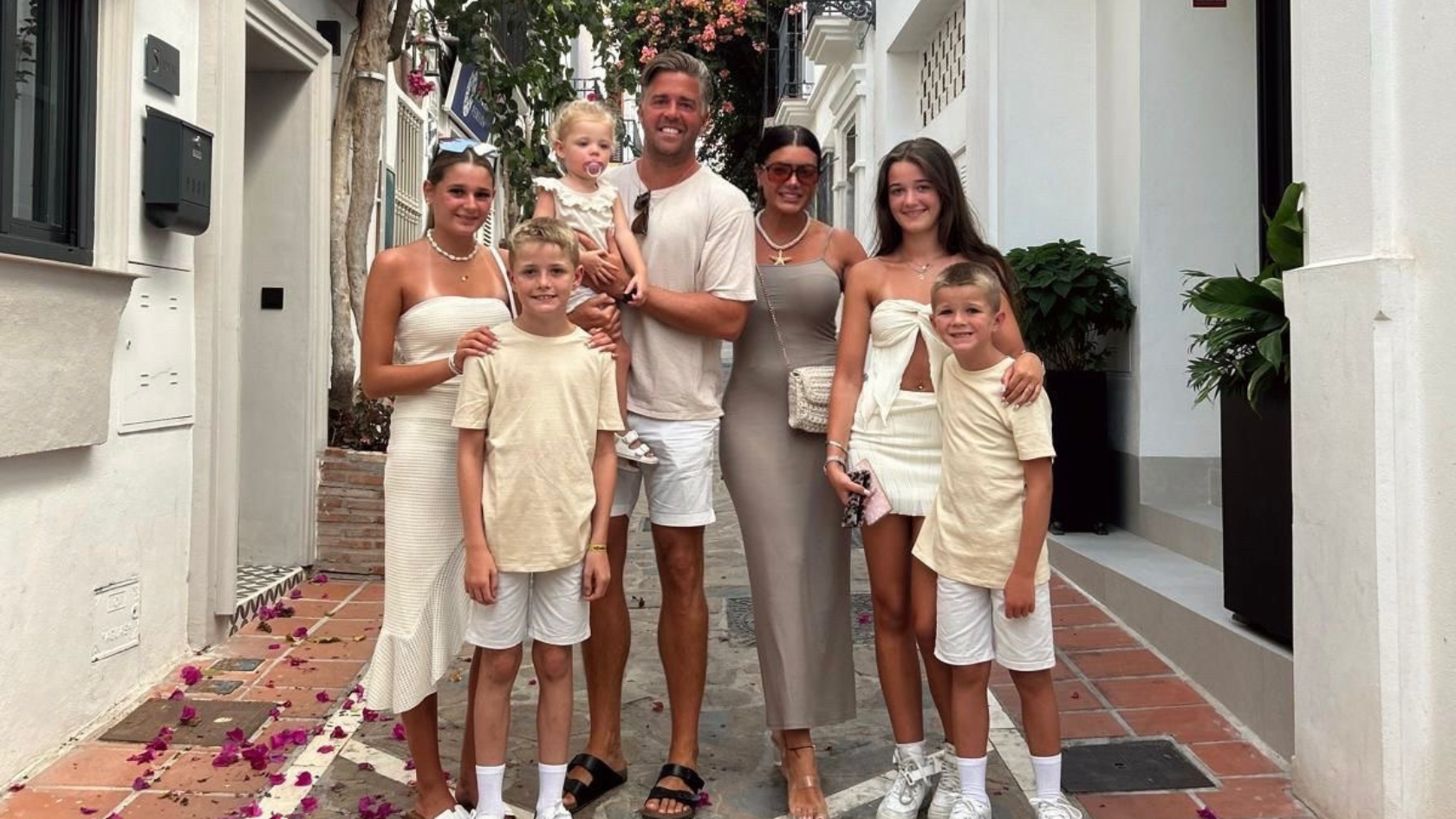 Matt holding his little girl, with his partner beside him and four other children. All wearing white on holiday.