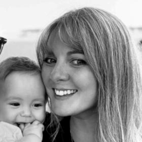 Leah and Josh smiling at the camera, holding baby George.