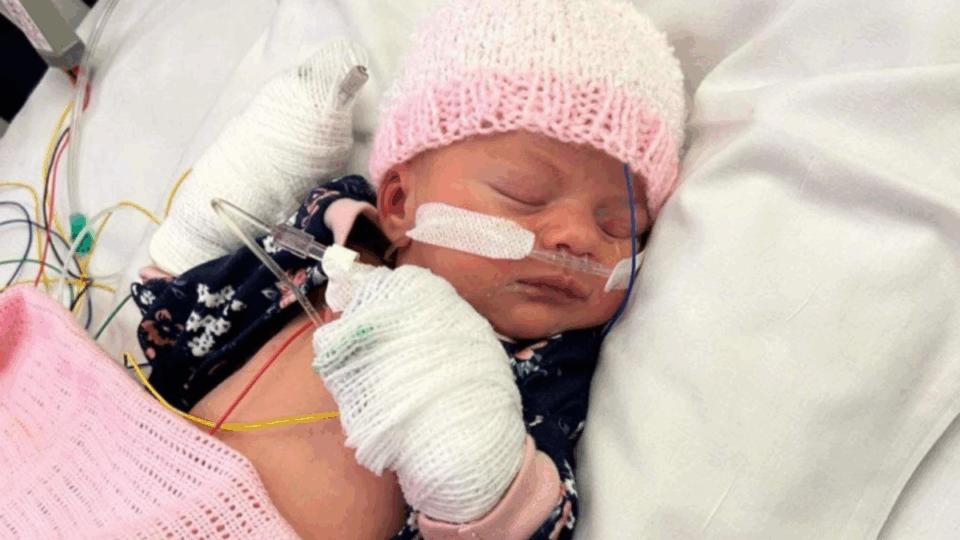 Baby Violet asleep, wearing a pink and white hat.