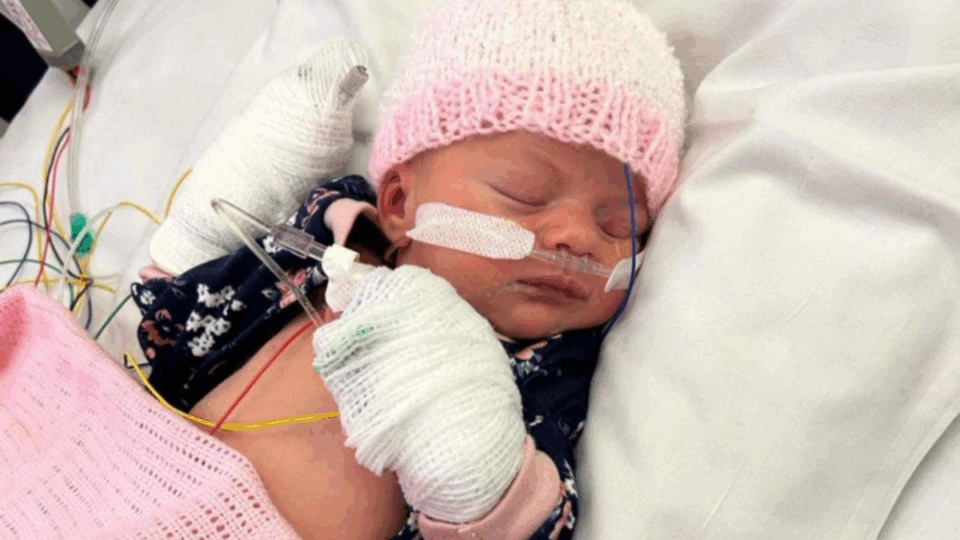 Baby Violet asleep, wearing a pink and white hat.