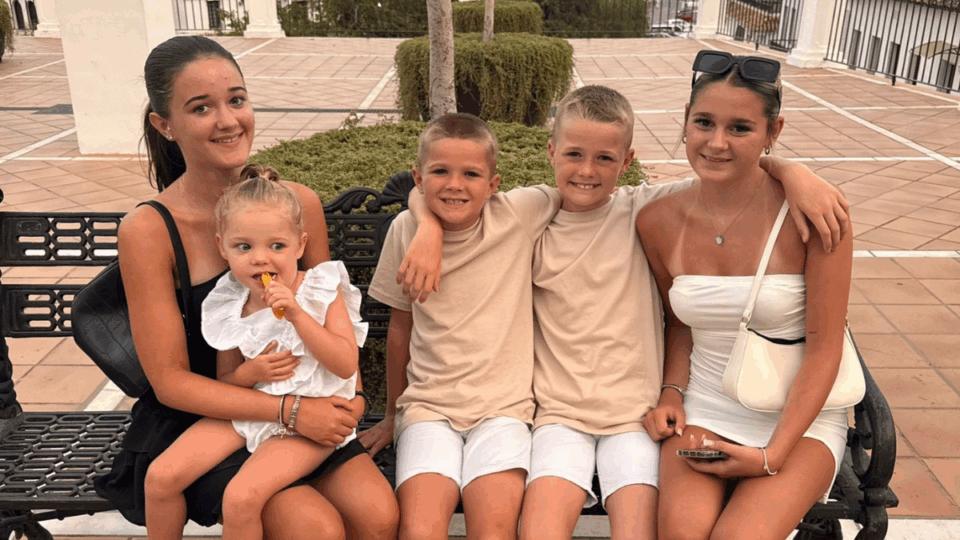 Matt's five children sitting on a bench with their arms around each other, smiling at the camera.