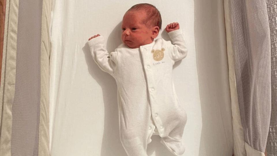 Baby in a sleep suit lying in a cot