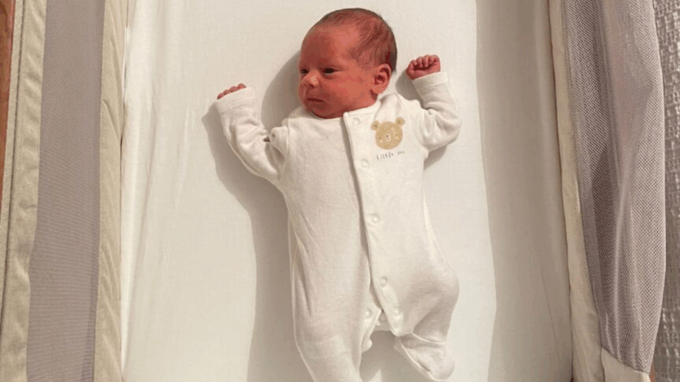 Baby in a sleep suit lying in a cot