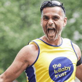 Abs wearing a Lullaby Trust running vest running, with his mouth wide open shouting, looking happy.