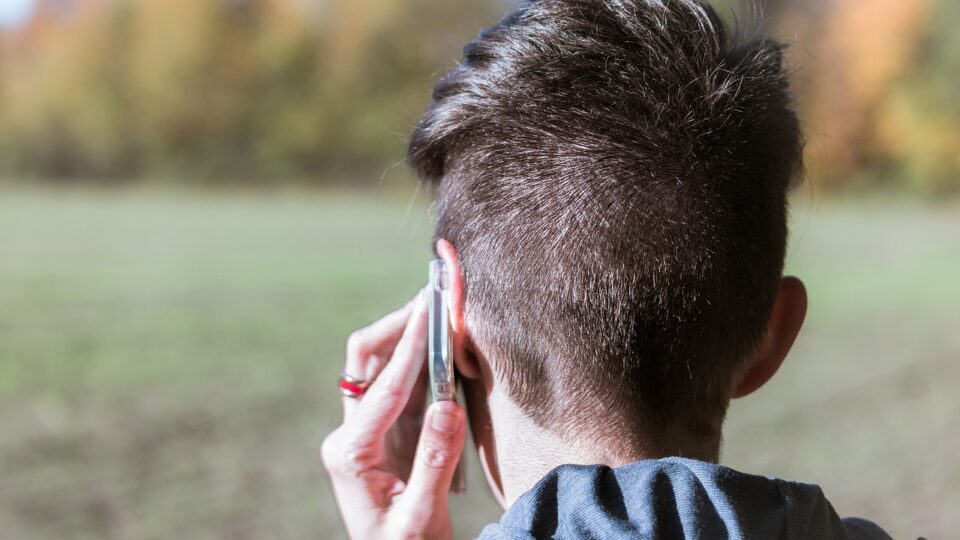 Man with the back of his head to the camera, with a phone to his ear.