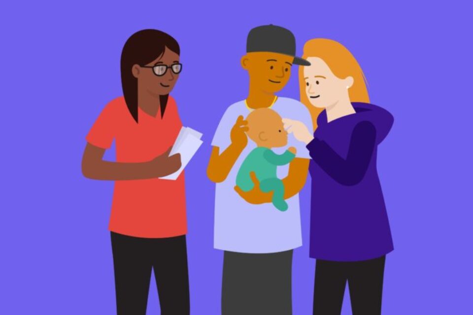 A professional is holding a leaflet talking to a family holding a baby