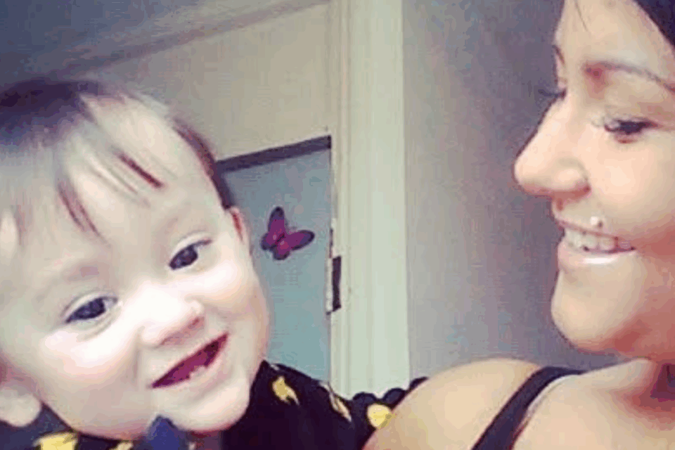 Paige holding her son, smiling at him. He has brown hair and is wearing a black top.
