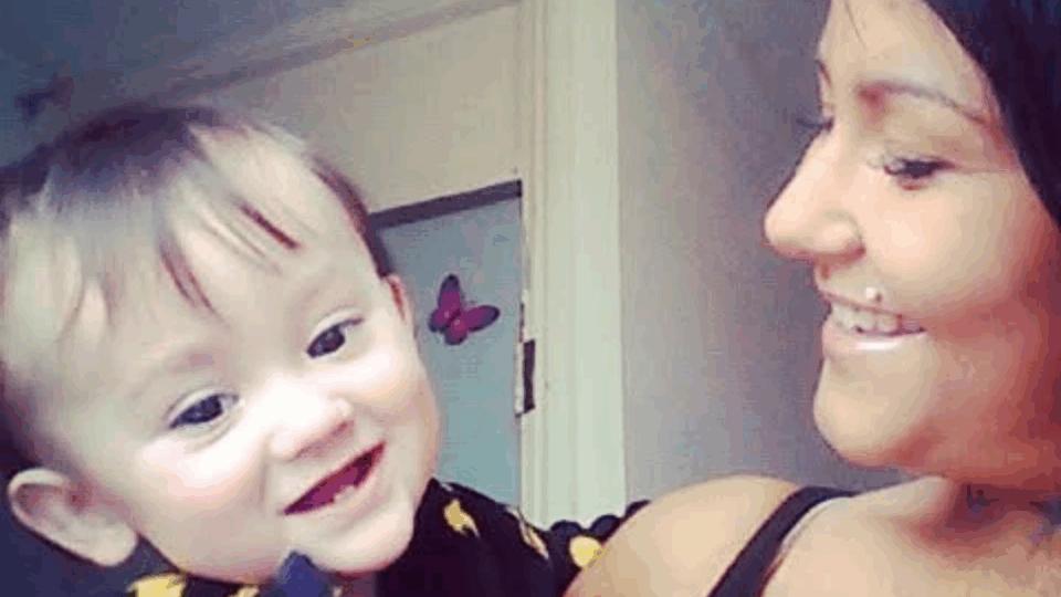 Paige holding her son, smiling at him. He has brown hair and is wearing a black top.