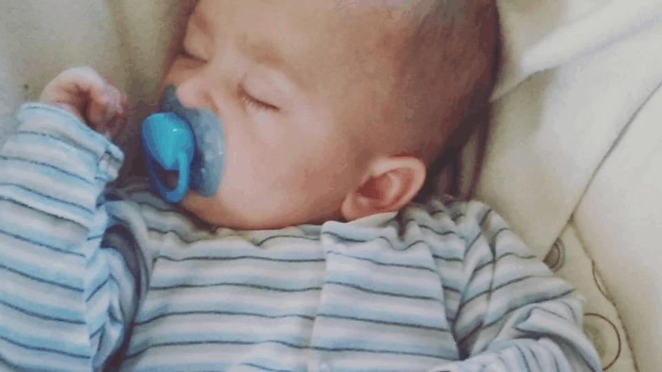 Baby with dummy and stripy babygrow