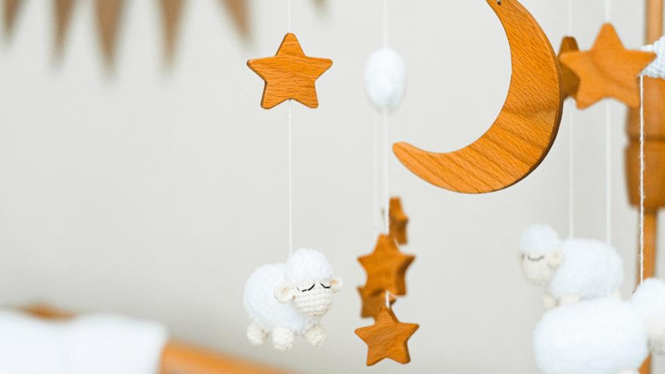 Dangling toys above a babys crib with stars, woolen sheep and moons.
